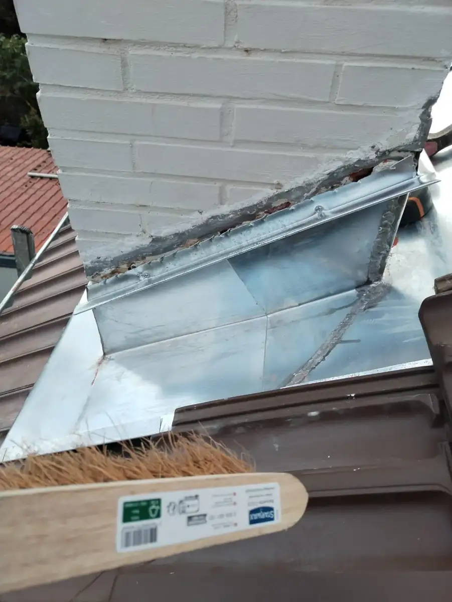 Bande de solin en zinc fixée contre la maçonnerie de la cheminée, au-dessus de l'abergement