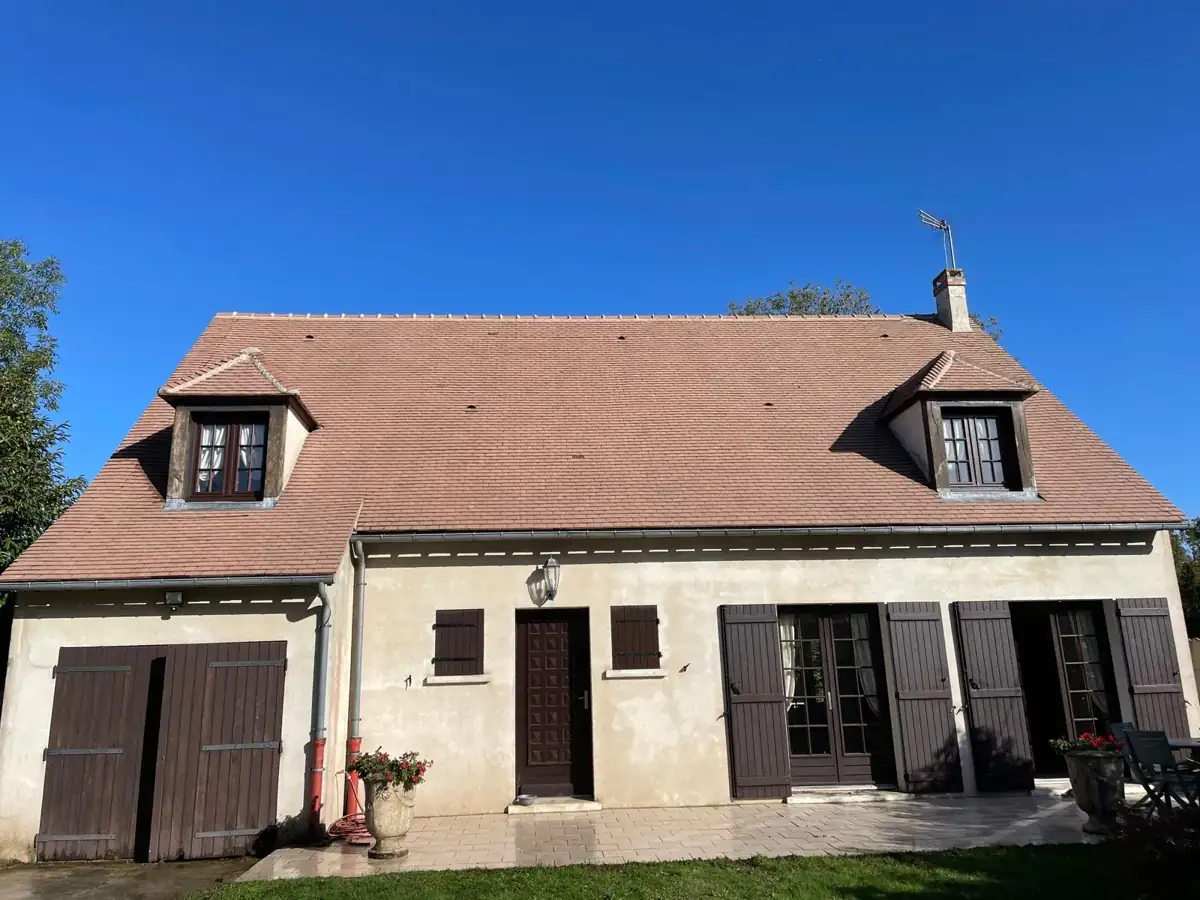 La même maison à deux lucarnes sous un ciel bleu, toiture nettoyée