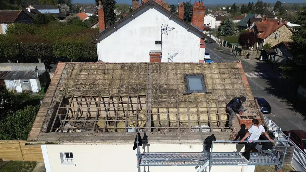 Toiture découverte, charpente et ancienne isolation à nu, compagnons au travail sur l'échafaudage